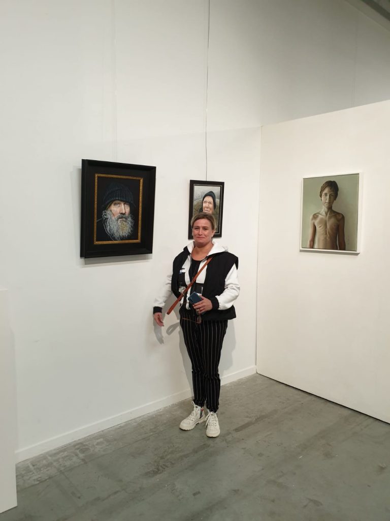 Edith staat naast haar portret van Pieter Derksen, achter haar zijn 2 andere portretten geexposeerd