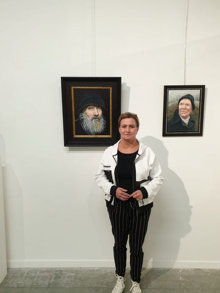 Edith staat tussen 2 portretten in, links haar portret van Pieter Derksen, rechts een portret van een man